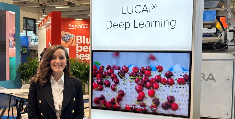Bendetta standing against a poster of LUCAi deep learning technology